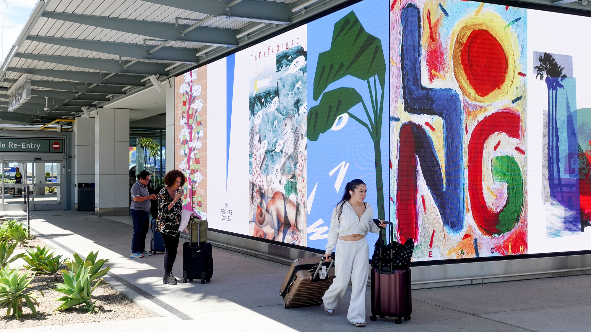 People viewing large, colorful artworks displayed outdoors in a public space.